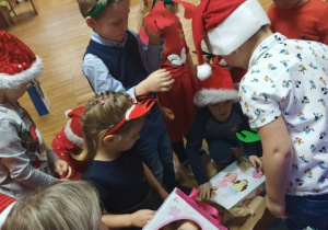 Dzieci otwierają prezenty od Mikołaja